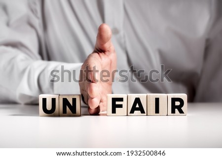 Businessman hand puts away the first two letters from the word unfair and transforms it into fair. Justice and fairness in business concept. Royalty-Free Stock Photo #1932500846