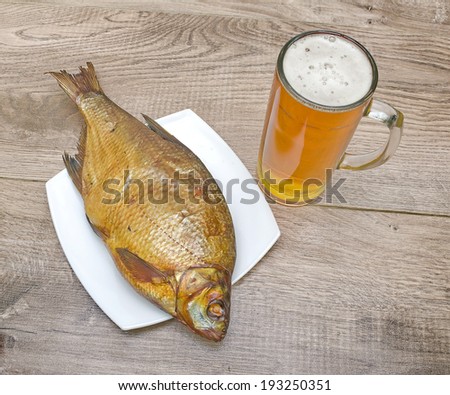 appetizing smoked bream and a glass of light beer on a wooden table. horizontal photo.
