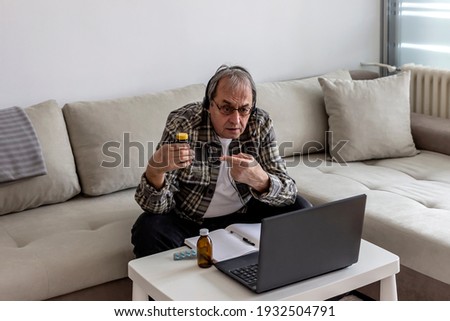 Photo of a senior man consulting with his doctor online on laptop. Mature man video chatting with doctor at home during Coronavirus lockdown. Senior man having video chat with pharmacist on computer.