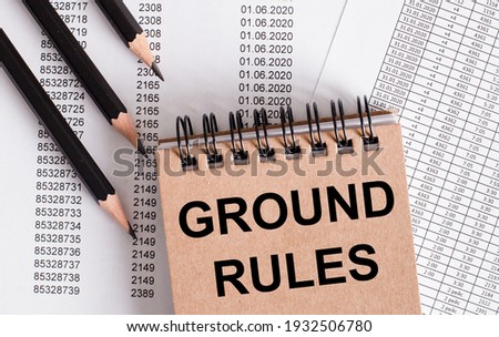 The words GROUND RULES is written on the brown notebook. Nearby pencils