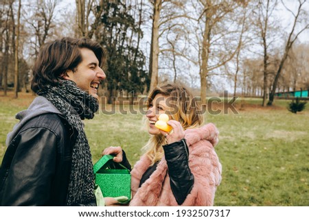 Happy couple in love having fun outdoors and smiling.Man giving to his woman a gift.