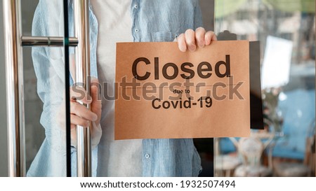 Sign Closed covid 19 lockdown on shop entrance door as new normal shutdown. Unrecognizable Woman in gloves hangs closed sign on front door of cafe. Lockdown coronavirus covid 19. Long web banner.