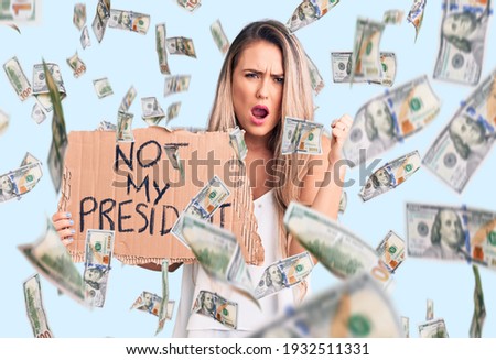 Young beautiful blonde woman holding not my president cardboard banner annoyed and frustrated shouting with anger, yelling crazy with anger and hand raised