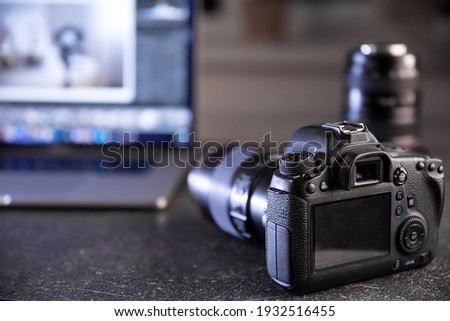 Professional camera on a blurred background with a laptop. The concept of working with photos and videos.