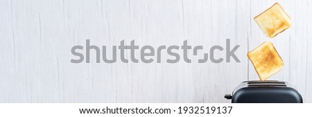Bread coming out of the toaster with minimalist wooden background