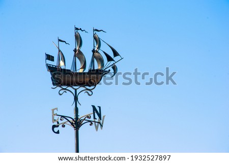 Weather vane in the form of a ship against the blue sky. Royalty-Free Stock Photo #1932527897