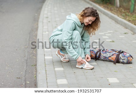 Fitness woman tying shoelaces outdoors Royalty-Free Stock Photo #1932531707
