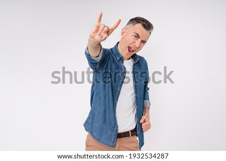 Excited caucasian middle-aged man showing rock-n-roll gesture isolated over white background