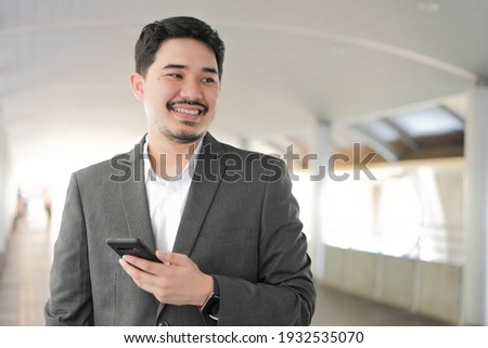 close up adult middle east businessman hold smartphone to checking stock market exchange or read news on online website at outside office in relax time for lifestyle business concept