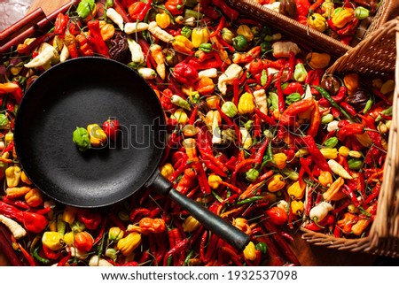 Creative picture of many types of spicy chilli peppers and black frying pan with peppers made like a traffic lights signals red yellow green