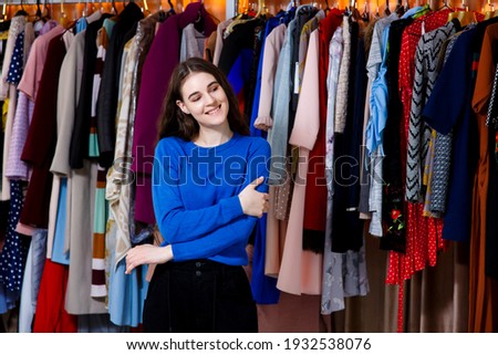 beautiful teenager posing to camera. Beautiful young woman near rack near hangers with clothing. shopping, fashion, style and people concept