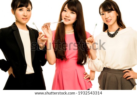 Three Asian girls holding toothbrushes on white background