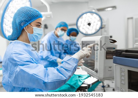 Anesthesiologist keeping track of vital functions of the body during cardiac surgery. Surgeon looking at medical monitor during surgery. Doctor checking monitor for patient health status.