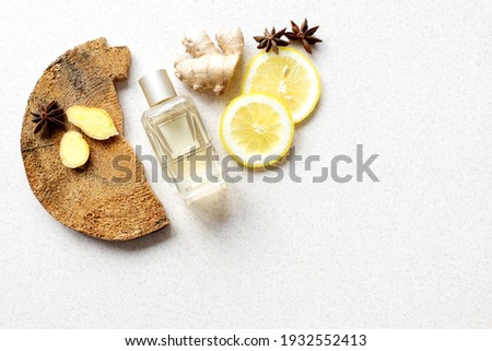 glass perfume bottle with lemon wedges, anise stars, wood bark and ginger fragments on beige background. fresh, woody, spicy unisex scent concept. Copy space Royalty-Free Stock Photo #1932552413
