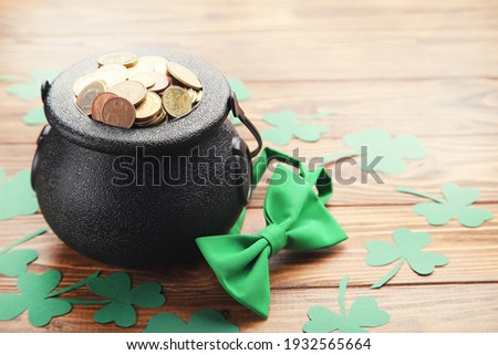 Pot of gold with bow tie and clover leafs on brown wooden background. Concept St.Patrick's Day