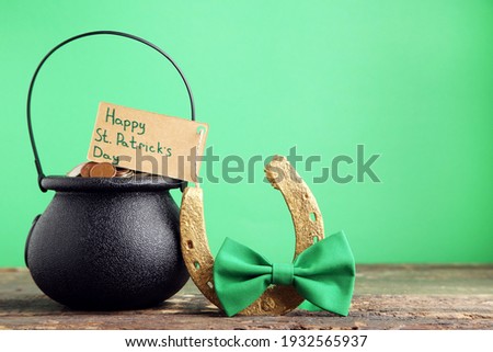 Pot of coins and card with text Happy St. Patricks Day, golden horseshoe and bow tie on green background