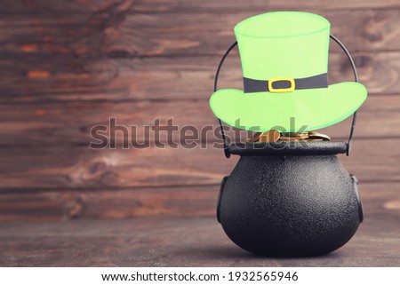 Pot of gold with bow tie and clover leaf on wooden brown background. Concept St.Patrick's Day.