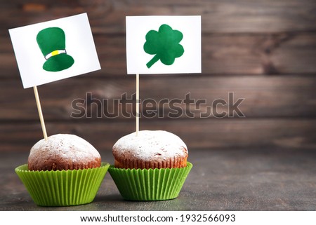 Cupcakes and flags with picture of St. Patrick's hat and clover leaf on wooden background