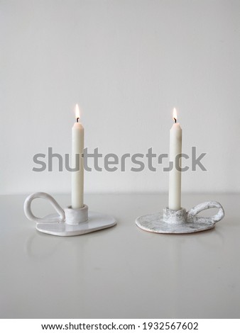 white candles ceramic candlestick minimalism white background  Royalty-Free Stock Photo #1932567602