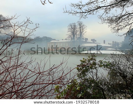 Dunham Hall across the lake in winter mist Royalty-Free Stock Photo #1932578018