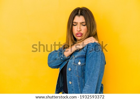 Young indian woman isolated on yellow background having a shoulder pain.