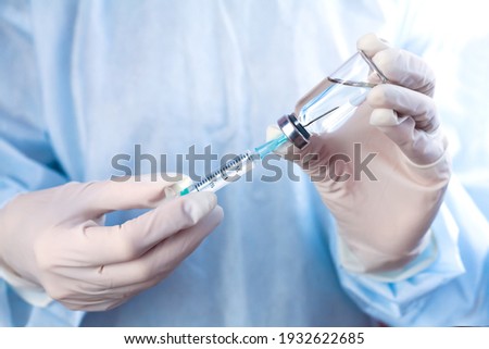 Influenza and coronavirus vaccination. Ddoctor or nurse holds syringe and medical injection in hands. Close-up. Royalty-Free Stock Photo #1932622685