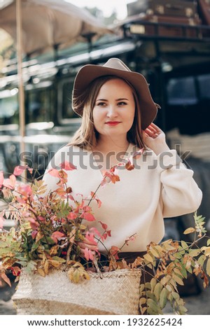 beautiful young girl is photographed in an autumn theme near the car