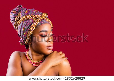 authentic mixed race boho fashion lady with makeup and silk turban over head in red studio background