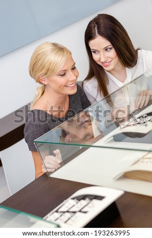 Two girls looking at window case with jewelry at jeweler's shop. Concept of wealth and luxurious life