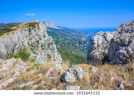 Mediterranean landscape. Forested rocks of the Black Sea coast of the southern coast of the Crimean Peninsula on a clear sunny day. View down from the rocky mountains to the sea