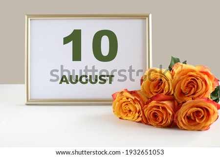 day of the month 10 August calendre photo frame and yellow rose on a white table