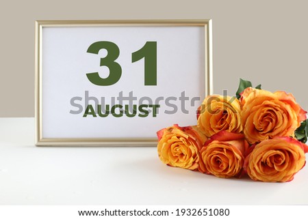 day of the month 31 August calendre photo frame and yellow rose on a white table