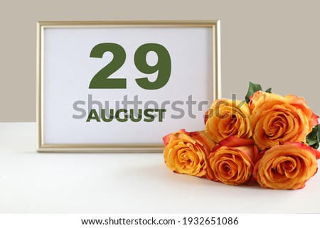 day of the month 29 August calendre photo frame and yellow rose on a white table