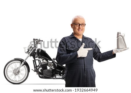 Motorbike mechanic holding an engine oil and posing in front of a chopper isolated on white background