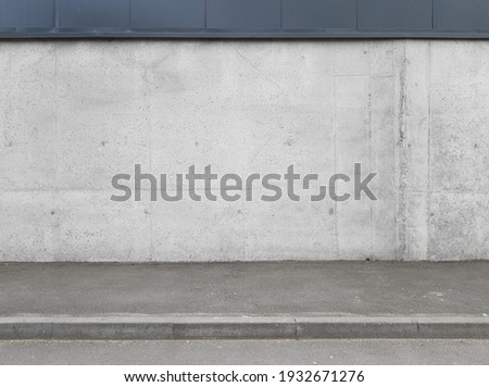 a fragment of an urban concrete wall of a building and an asphalt sidewalk, a building facade, a template or source Royalty-Free Stock Photo #1932671276