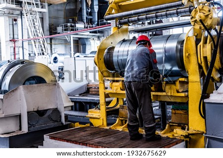 Worker and stock with rolls of sheet steel in industrial plant Royalty-Free Stock Photo #1932675629