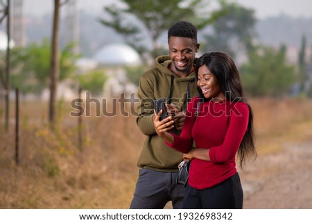 young black man and woman checking something on a phone together Royalty-Free Stock Photo #1932698342