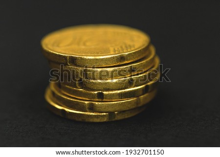 One stack of golden euro coins on black background, macro photo