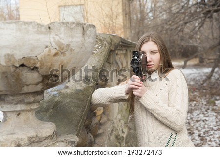 Outdoor Portrait of beautiful caucasian cute woman with brown long hair holding vintage 8mm camera in hands Outdoor in winter snowy park and based on old retro concrete fence