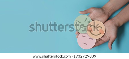 Hand holding paper cut happy smile, bore and angry face on blue background, positive thinking, mental health assessment , world mental health day concept Royalty-Free Stock Photo #1932729809