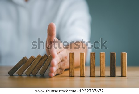 Hand Stopping the domino business crisis effect or risk protection concept, business solution and intervention Royalty-Free Stock Photo #1932737672