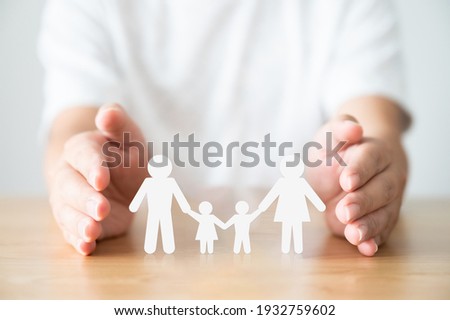 Hand protecting family on wood table. Healthcare and life insurance concept Royalty-Free Stock Photo #1932759602
