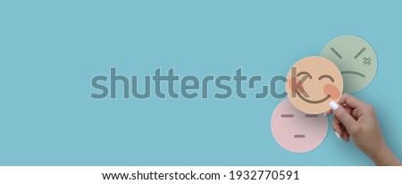 Woman hand choosing happy smile face paper cut, feedback rating and positive customer review, experience, satisfaction survey ,mental health assessment, world mental health day concept Royalty-Free Stock Photo #1932770591