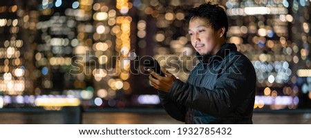 Banner and web page or cover template of Asian man using smart mobile phone with smile action over the photo blurred of New york Cityscape, USA downtown, career working everywhere concept