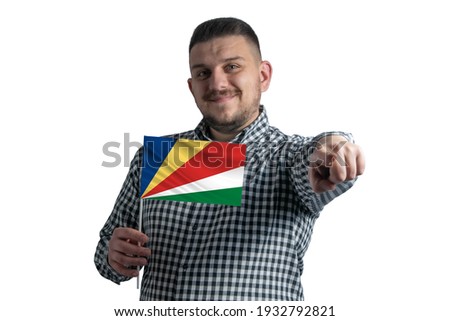 White guy holding a flag of Seychelles and points forward in front of him isolated on a white background.