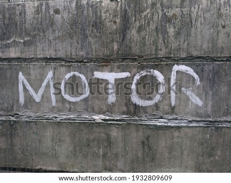 a dark gray concrete wall, bearing the words "motor" in white