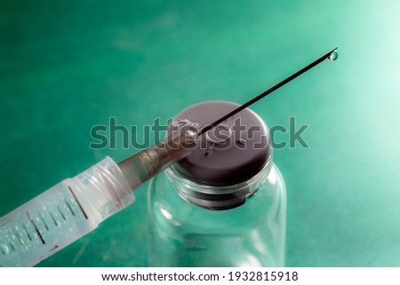 selective focus on drop of syringe and vial for vaccine on a green background, in Brazil