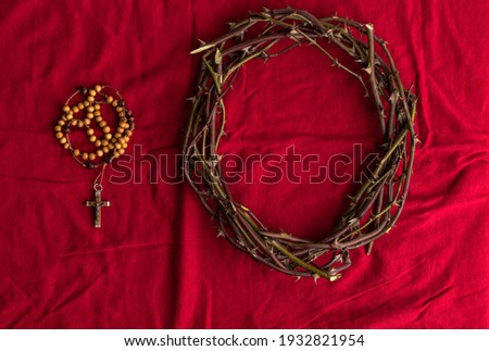 Crown of thorns and Rosary beads on red background. Easter and Christianity symbols with copy space.