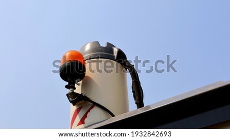 Orange alarm on the car roof. Emergency light on the milling machine warns of danger while heavy machinery is working in blue sky background with copy space. Selective focus