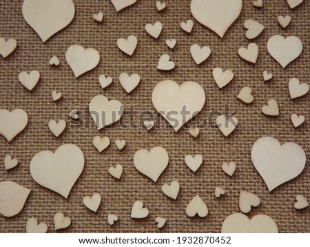 wooden hearts of different sizes on jute fabric as a Valentine's day greeting card.  